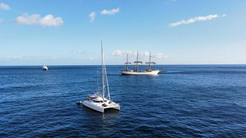 Savannah Yacht Photos Pics 1998 Fountaine Pajot Bahia 46 catamaran sailing on open sea with ships in background.
