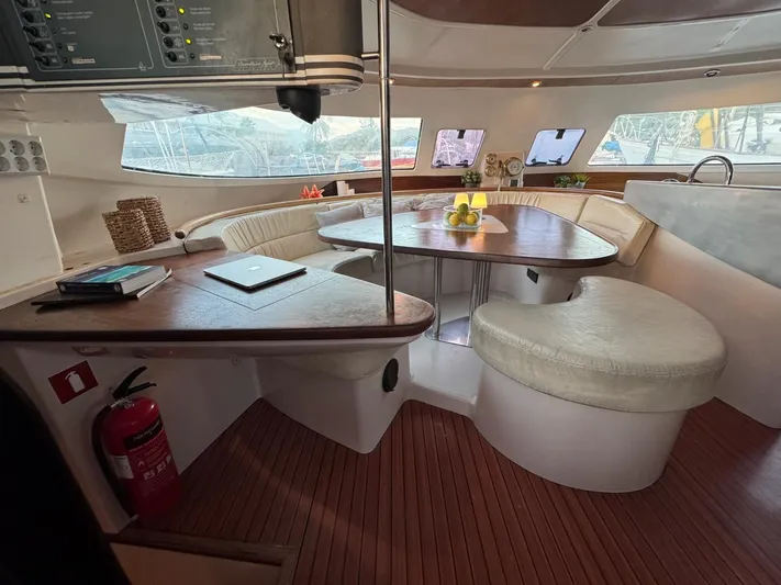 Savannah Yacht Photos Pics Interior of 1998 Fountaine Pajot Bahia 46 catamaran with wooden table and cushioned seating.