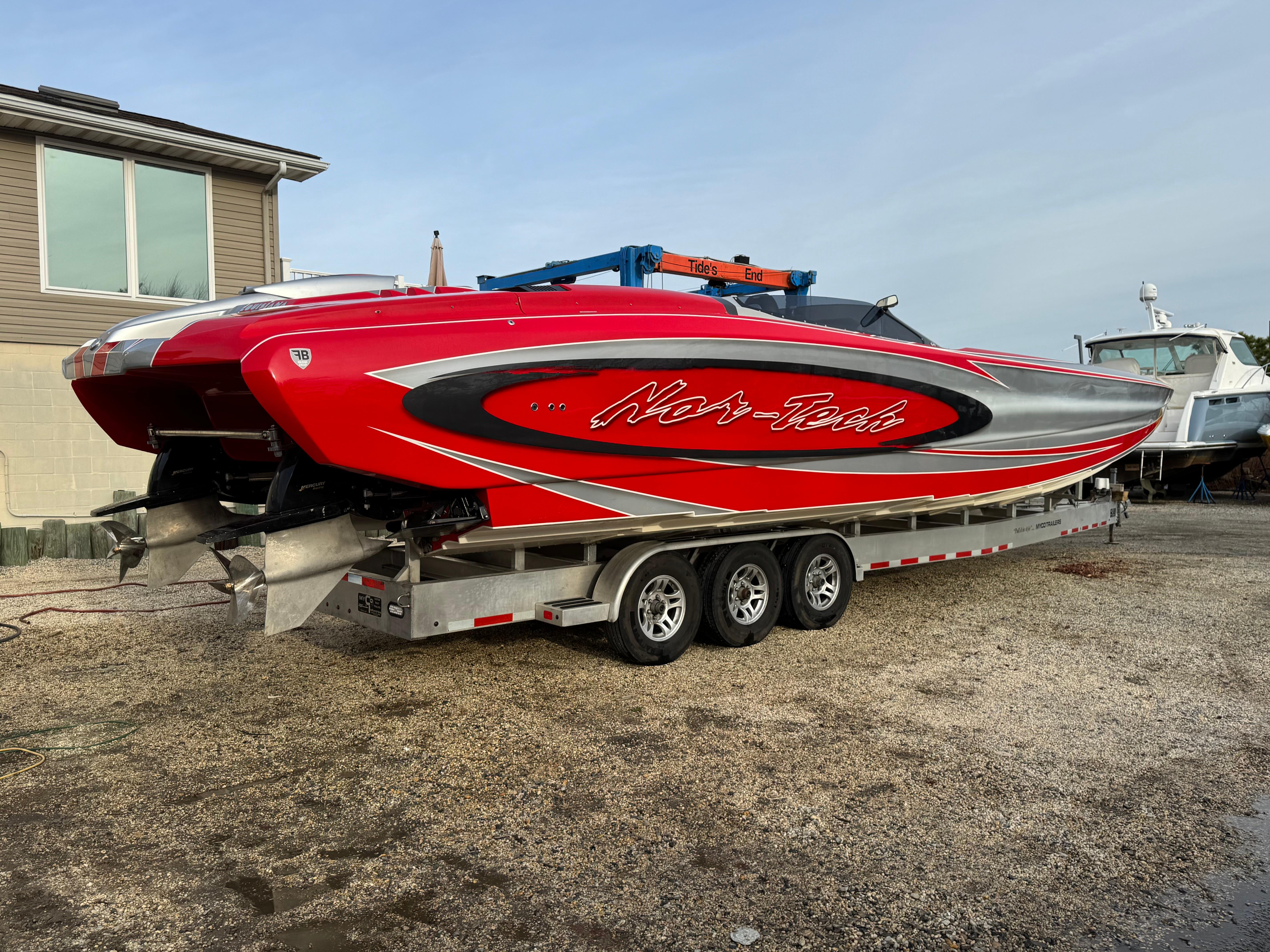 Red 2010 Nor-Tech 4000 Roadster boat on a trailer, parked outdoors.