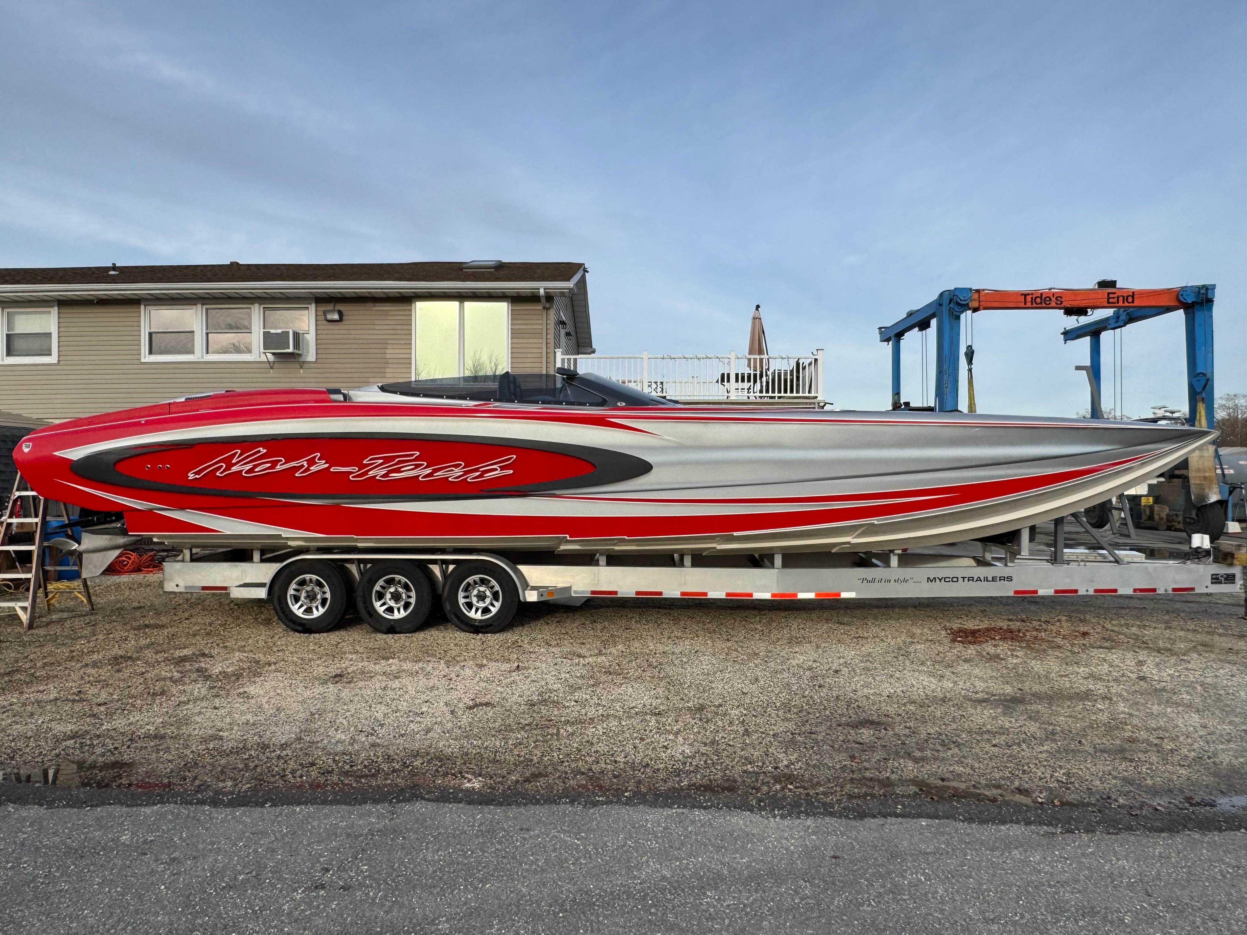 2010 Nor-Tech 4000 Roadster boat on trailer, featuring sleek red and silver design.