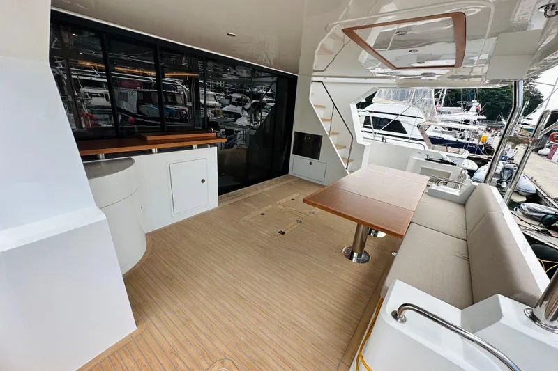  Yacht Photos Pics Luxurious 2022 ILIAD 50 yacht deck with seating, table, and marina view.