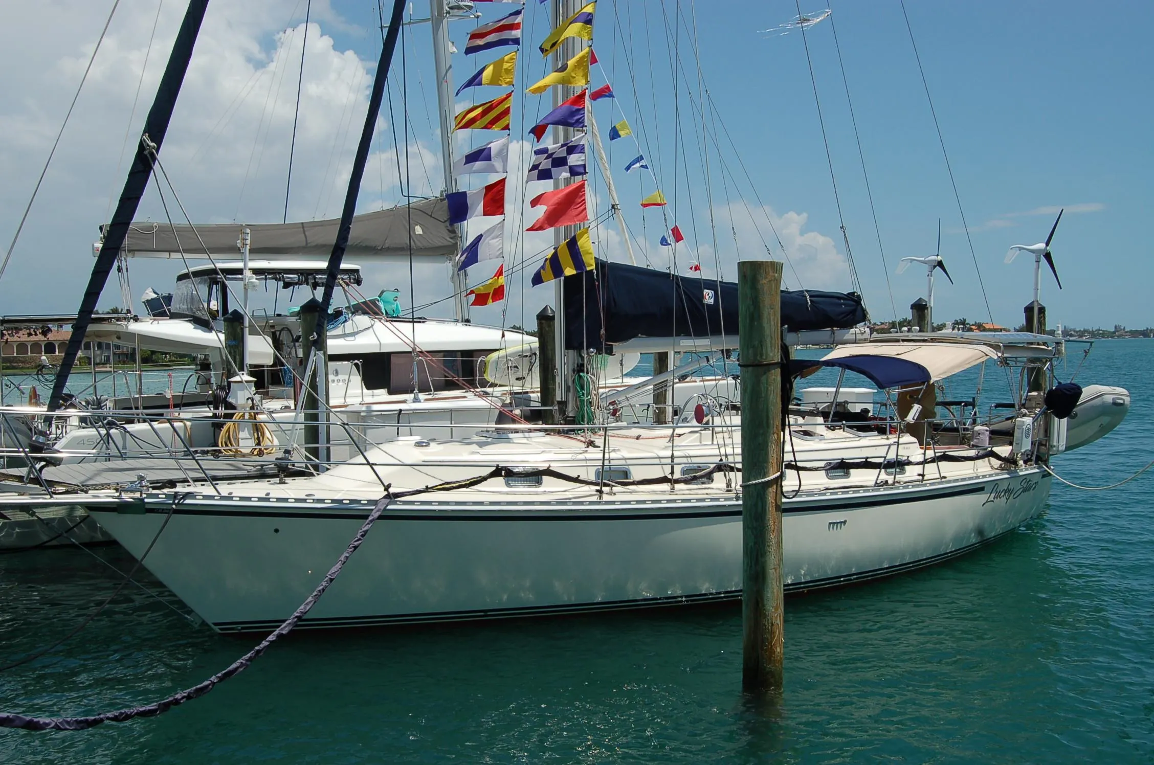 2005 Caliber 40 LRC SE sailboat docked, adorned with colorful flags, in a sunny marina.
