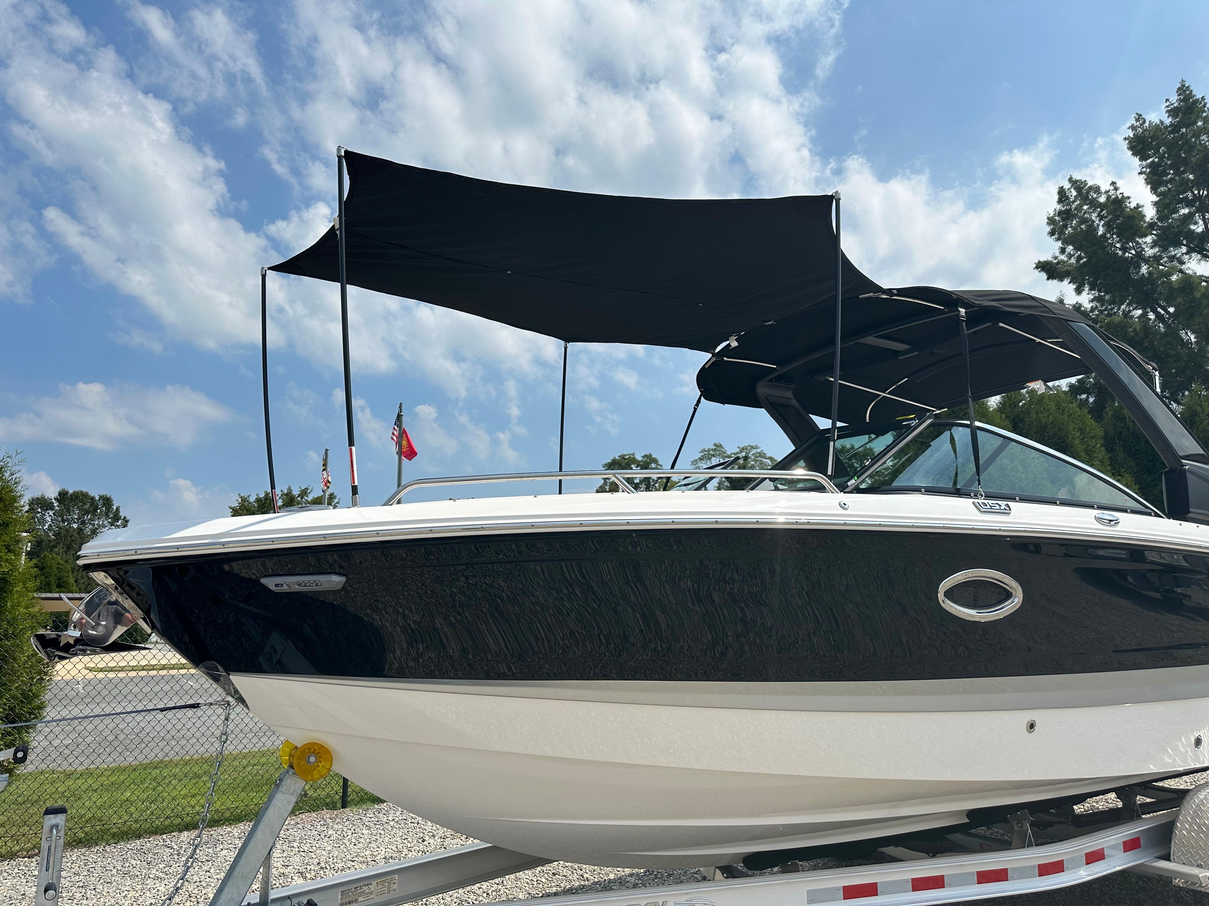 2025 Chaparral 270 OSX boat on trailer, black canopy, clear sky background.
