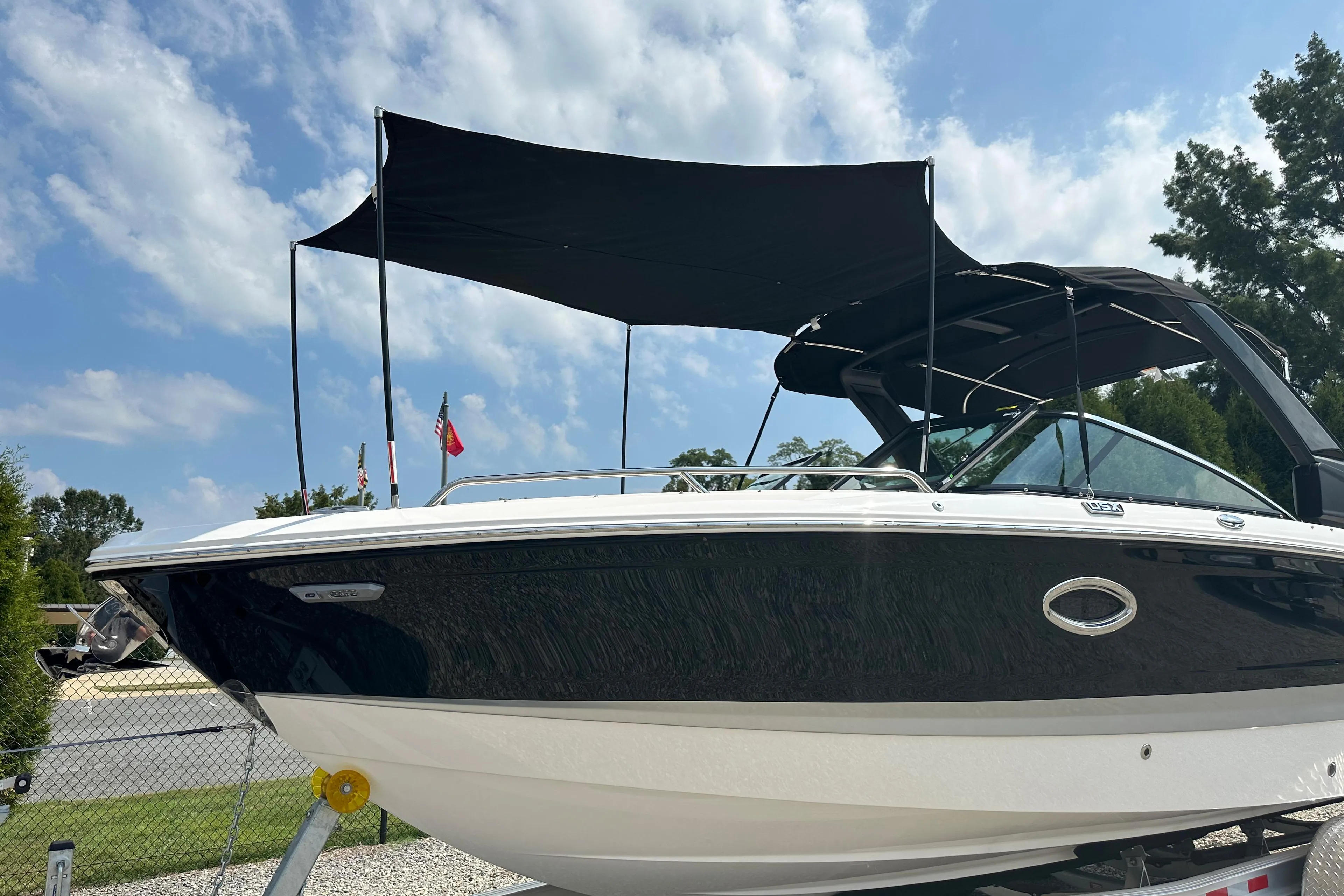 2025 Chaparral 270 OSX boat on trailer, black canopy, clear sky background.