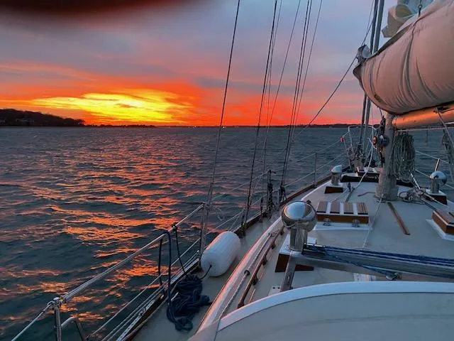 Entangled Yacht Photos Pics Sailing yacht Shannon 43 at sunset, 1988 model, on calm waters with vibrant sky.