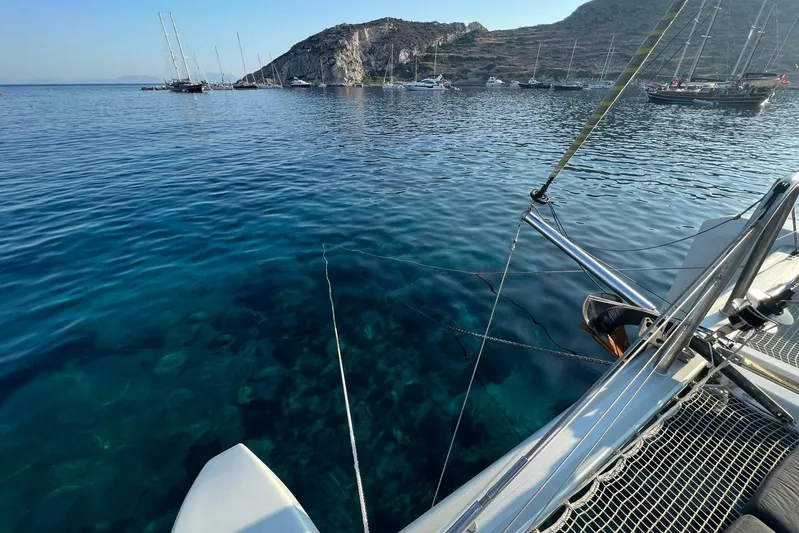 Chicago Yacht Photos Pics Lagoon 52 F catamaran anchored in clear blue waters near rocky coastline, 2020 model.