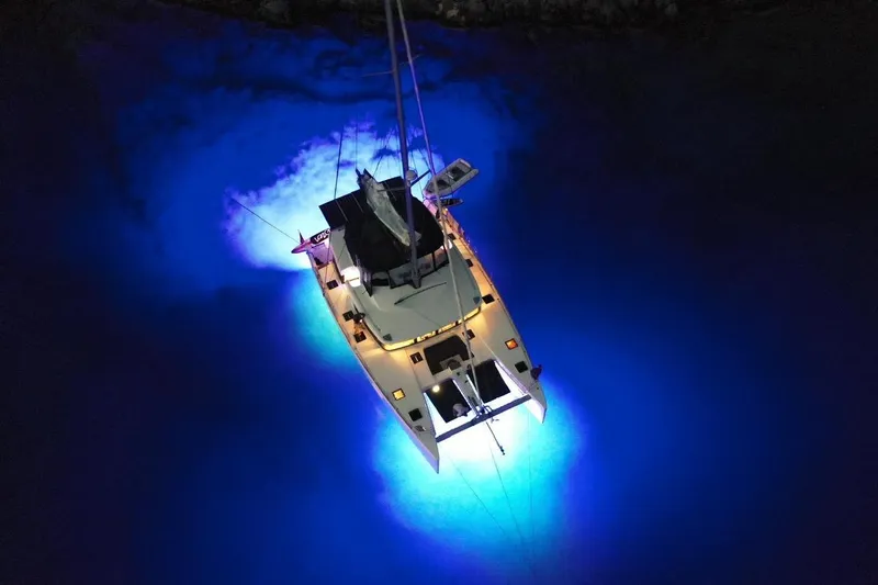 Chicago Yacht Photos Pics Aerial view of illuminated 2020 Lagoon 52 F catamaran at night, glowing in blue water.