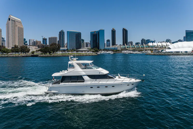 All Falked Up Yacht Photos Pics 1999 Carver 530 Voyager Pilothouse yacht cruising near city skyline on a sunny day.