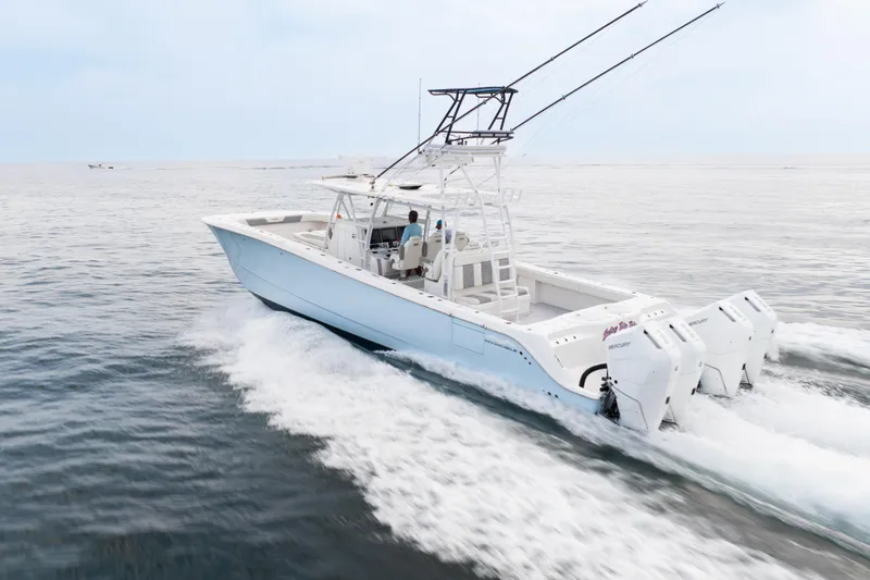 Seeking Twin Tales Yacht Photos Pics 2022 Invincible 46 Catamaran cruising on open water, showcasing powerful outboard engines.