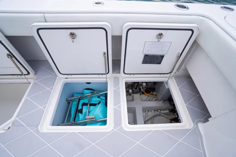 Seeking Twin Tales Yacht Photos Pics Open storage compartments on 2022 Invincible 46 Catamaran deck, revealing equipment and machinery.