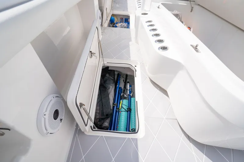 Seeking Twin Tales Yacht Photos Pics Storage compartment on 2022 Invincible 46 Catamaran, featuring fishing rods and sleek design.