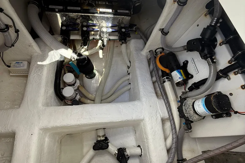 Seeking Twin Tales Yacht Photos Pics Engine compartment of 2022 Invincible 46 Catamaran, showcasing intricate plumbing and wiring systems.