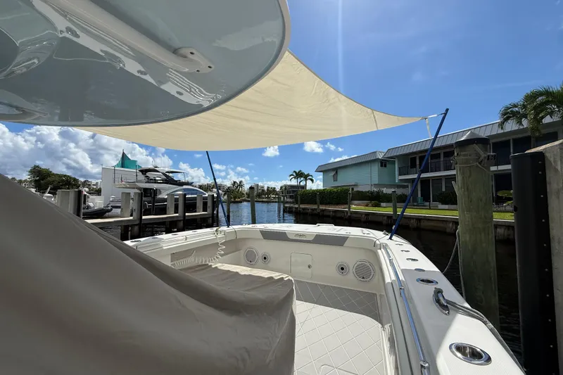 Seeking Twin Tales Yacht Photos Pics 2022 Invincible 46 Catamaran docked, featuring spacious deck and sunshade under clear blue sky.