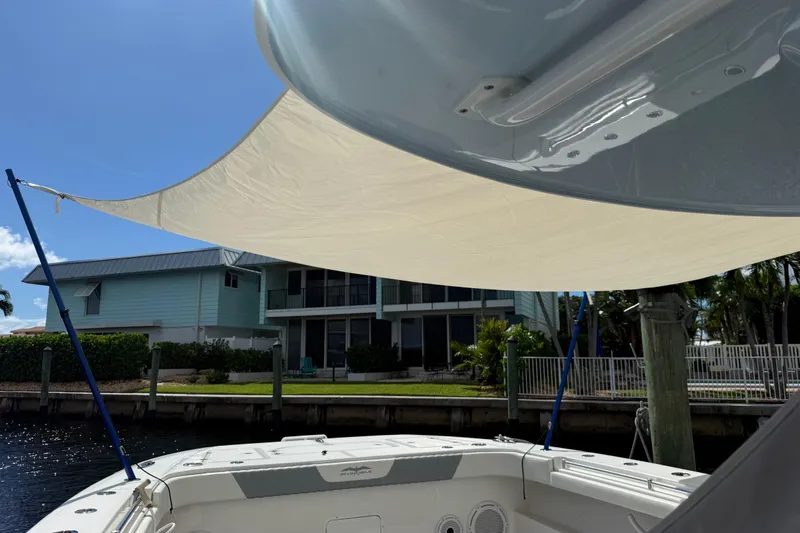 Seeking Twin Tales Yacht Photos Pics 2022 Invincible 46 Catamaran with sunshade, docked near waterfront home.