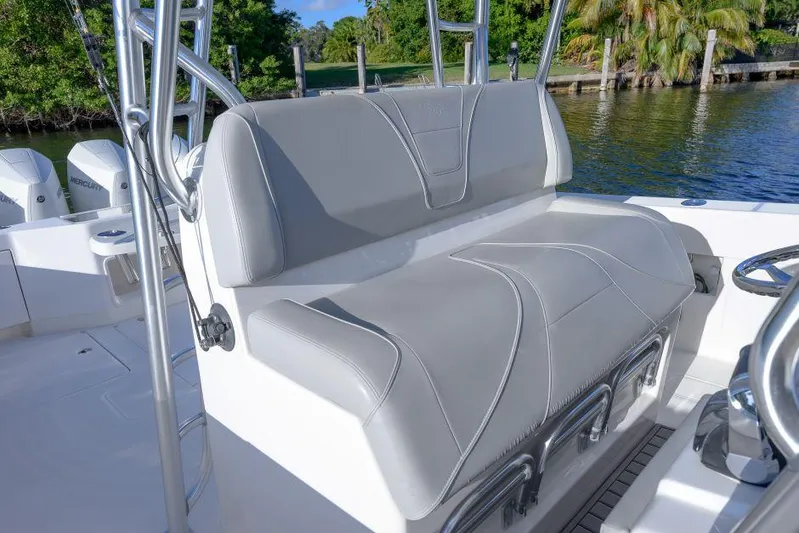  Yacht Photos Pics 2022 SeaVee 390Z boat with gray cushioned seating, docked by lush greenery.