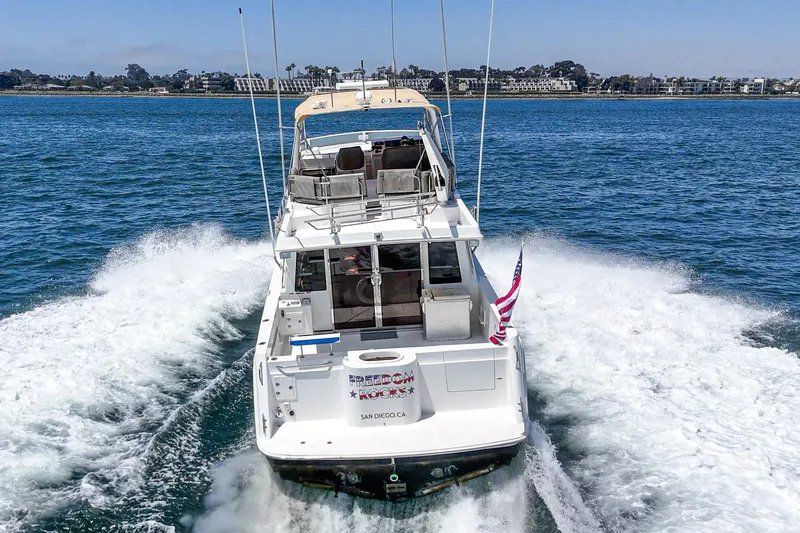 Freedom Rocks Yacht Photos Pics 2004 Navigator Rival 57 yacht cruising on open water, rear view with American flag.