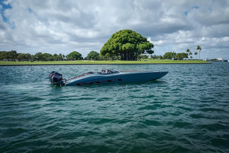  Yacht Photos Pics 2024 MTI 390X speedboat cruising on a scenic lake with lush greenery.