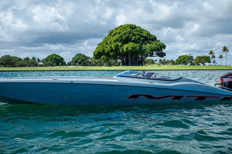  Yacht Photos Pics 2024 MTI 390X speedboat on water with lush green trees in the background.
