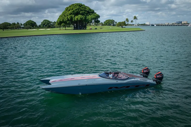  Yacht Photos Pics 2024 MTI 390X powerboat cruising on a scenic lake with lush greenery.