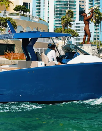 Mine Yacht Photos Pics 2022 Tesoro T38 Outboard boat cruising near modern waterfront buildings.