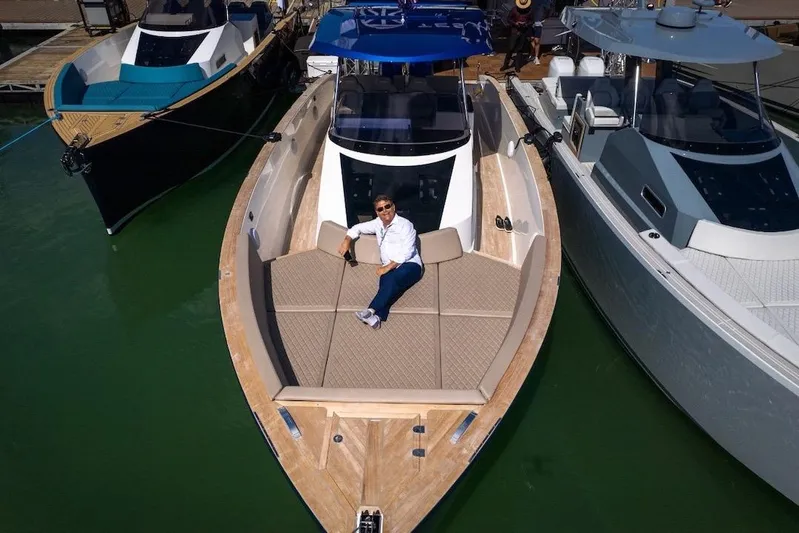 Mine Yacht Photos Pics 2022 Tesoro T38 Outboard boat with person relaxing on deck, docked between other boats.