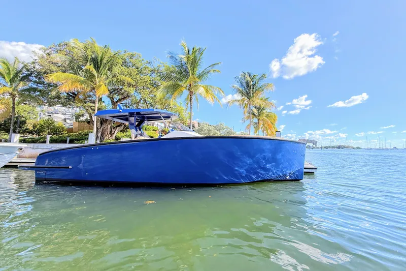 Mine Yacht Photos Pics 2022 Tesoro T38 Outboard boat docked by palm trees on a sunny day.