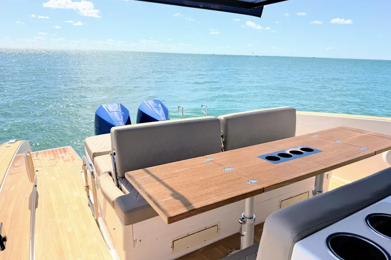Mine Yacht Photos Pics 2022 Tesoro T38 Outboard boat with seating and table, overlooking serene ocean view.