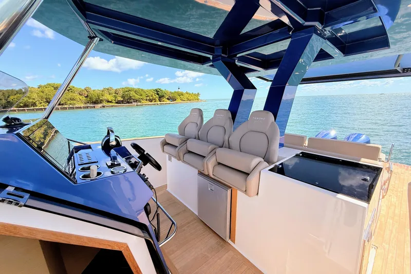 Mine Yacht Photos Pics 2022 Tesoro T38 Outboard boat interior with luxurious seating and modern controls, overlooking serene waters.