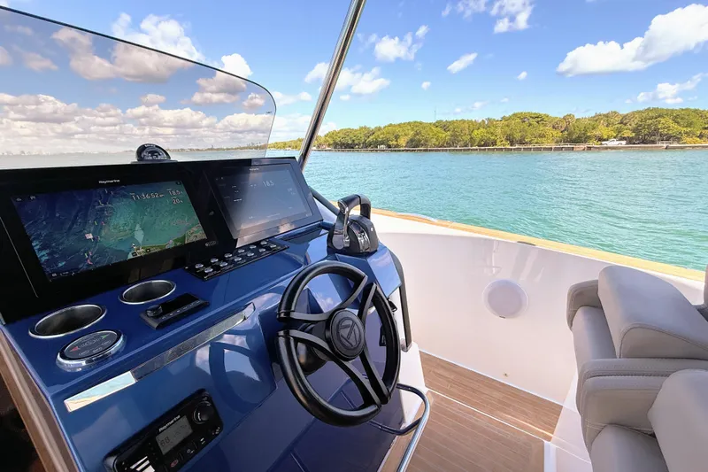 Mine Yacht Photos Pics 2022 Tesoro T38 Outboard helm with navigation screens, steering wheel, and scenic water view.
