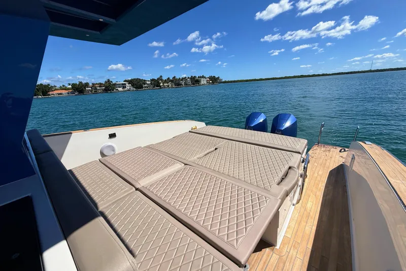 Mine Yacht Photos Pics Luxurious 2022 Tesoro T38 Outboard boat with sunbed, overlooking serene blue waters.