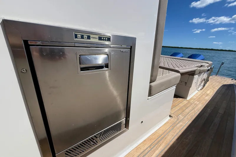 Mine Yacht Photos Pics 2022 Tesoro T38 Outboard boat with stainless steel appliance and cushioned seating by the water.