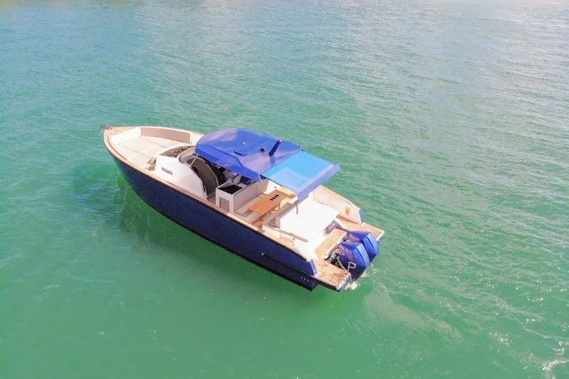 Mine Yacht Photos Pics 2022 Tesoro T38 Outboard boat on calm green water, featuring a blue canopy.