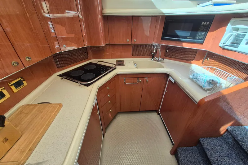 Funny Cide Yacht Photos Pics 1999 Sea Ray 420 Aft Cabin kitchen with wood cabinetry, stove, and microwave.