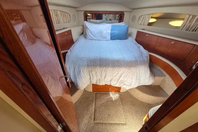 Funny Cide Yacht Photos Pics Cozy bedroom in 1999 Sea Ray 420 Aft Cabin yacht with wood accents and soft lighting.