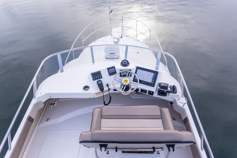  Yacht Photos Pics 2021 Cutwater C-32 CB boat helm with modern navigation equipment and seating on calm water.