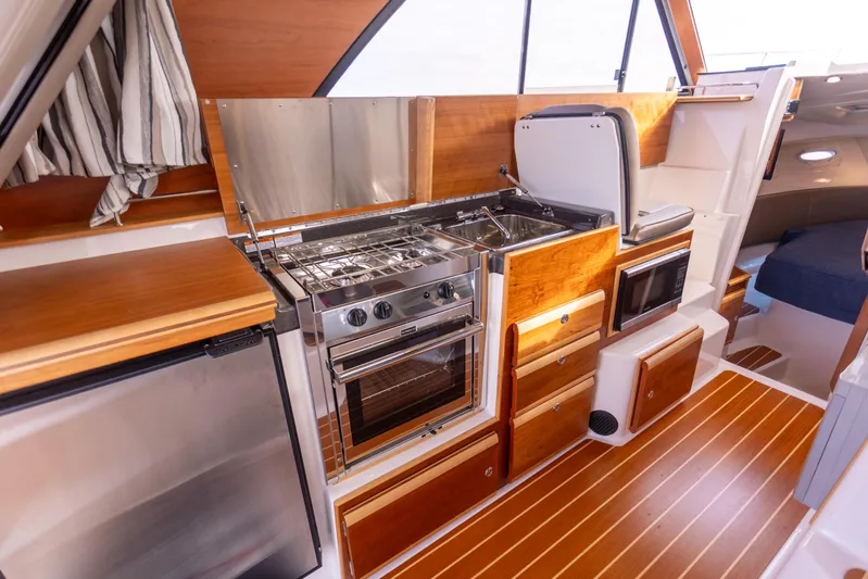  Yacht Photos Pics 2021 Cutwater C-32 CB yacht kitchen with wood cabinetry, stainless steel appliances, and modern design.