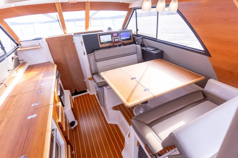  Yacht Photos Pics 2021 Cutwater C-32 CB interior with wood accents, dining area, and navigation equipment.