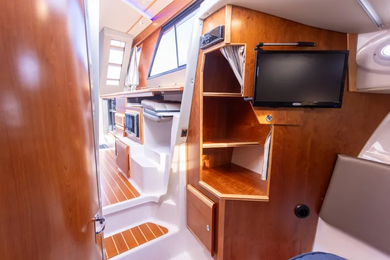  Yacht Photos Pics 2021 Cutwater C-32 CB interior with wood finish, shelves, and mounted TV.