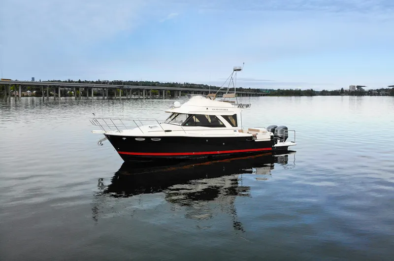  Yacht Photos Pics 2021 Cutwater C-32 CB boat on calm water with bridge in background.