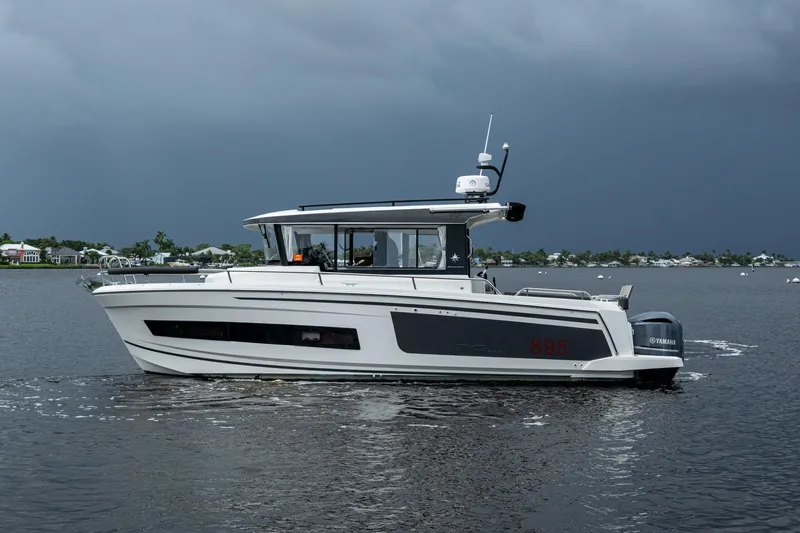 Yacht Photos Pics 2021 Jeanneau NC Sport 895 boat cruising on a calm lake under cloudy skies.
