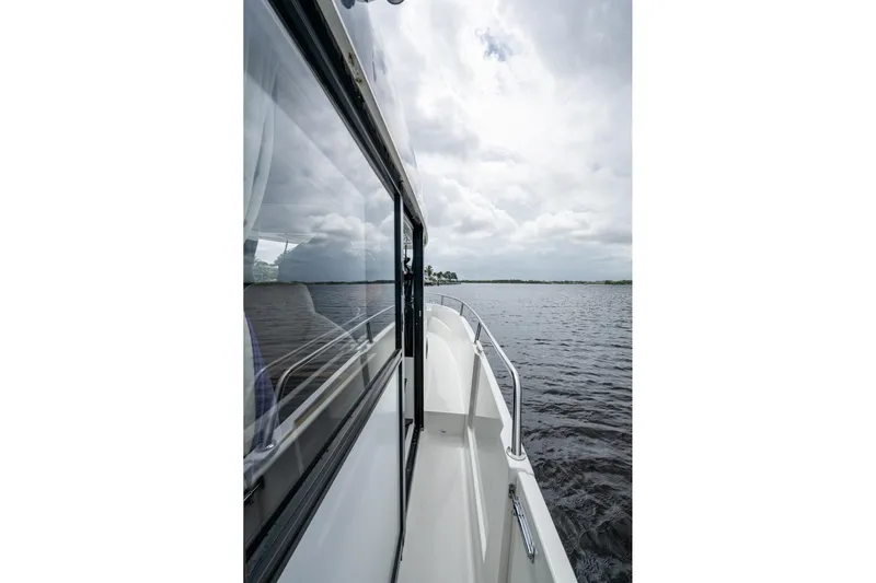  Yacht Photos Pics 2021 Jeanneau NC Sport 895 cruising on a calm lake under cloudy skies.