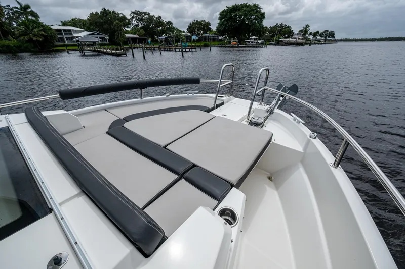  Yacht Photos Pics 2021 Jeanneau NC Sport 895 boat with cushioned deck, docked by a scenic waterfront.