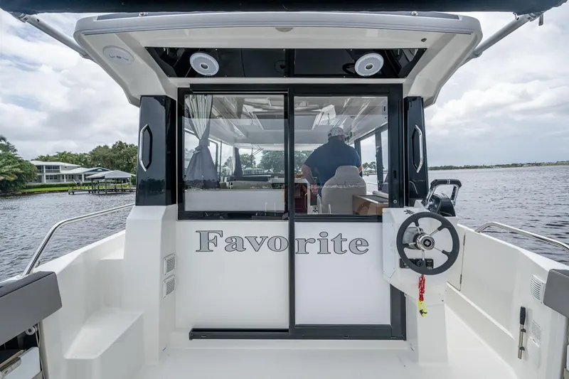  Yacht Photos Pics 2021 Jeanneau NC Sport 895 boat with "Favorite" on the stern, docked on a calm waterway.