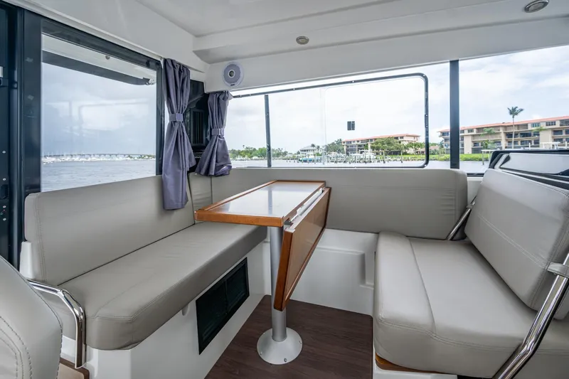  Yacht Photos Pics Interior of 2021 Jeanneau NC Sport 895 boat with seating and table, overlooking marina.