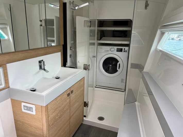 Levante Yacht Photos Pics Modern yacht bathroom with washer, sleek sink, and wooden cabinetry on Xquisite Yachts X5 PLUS 2022.