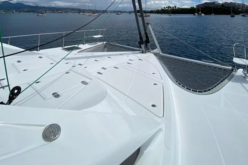 Levante Yacht Photos Pics 2022 Xquisite Yachts X5 PLUS catamaran deck with netting, anchored in a scenic harbor.