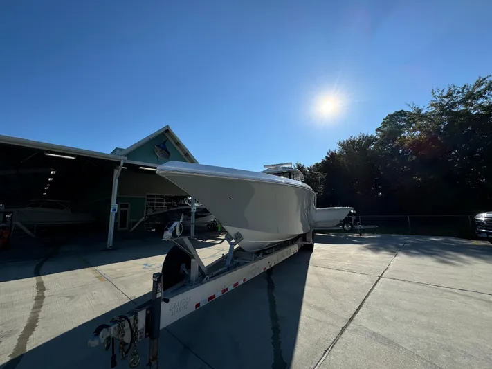 Yacht Photos Pics 2025 Fountain 38TE boat on trailer under bright sun, parked near a building.
