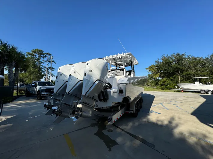  Yacht Photos Pics 2025 Fountain 38TE boat with triple outboard engines on a trailer in a sunny parking lot.