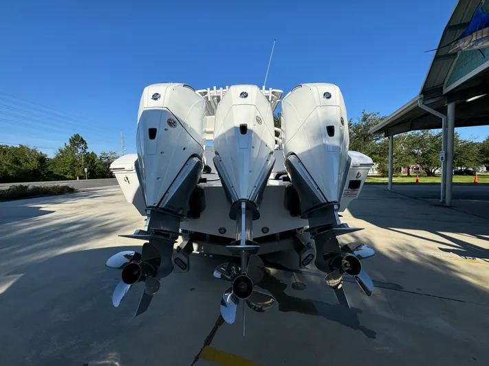  Yacht Photos Pics 2025 Fountain 38TE boat with triple outboard engines, parked outdoors under clear blue sky.