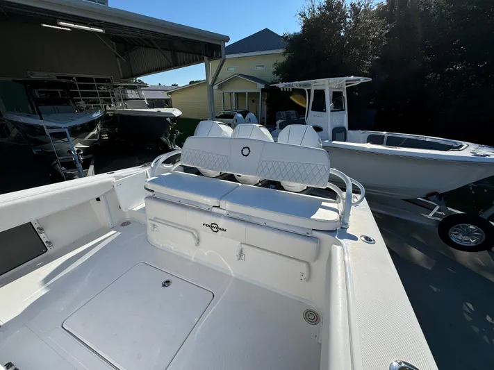 Yacht Photos Pics 2025 Fountain 38TE boat with white seating, docked near other boats.